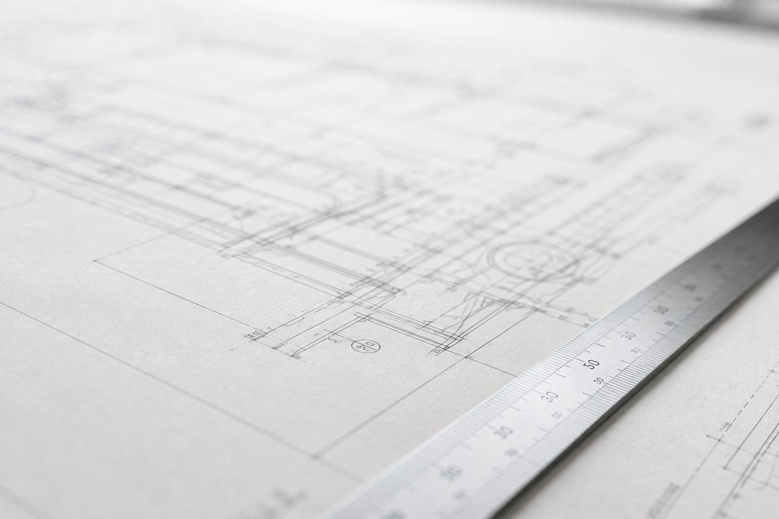 Large-format technical drawing on a drafting table with a scale ruler